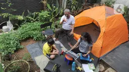 Warga bekerja menggunakan laptop di halaman rumahnya di kawasan Cinere, Depok, Senin (23/3/2020). Imbauan pemerintah untuk bekerja dari rumah atau work from home untuk mencegah penularan virus corona, dimanfaatkan warga dengan beragam aktivitas. (merdeka.com/Arie Basuki)