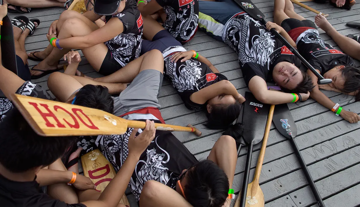 Para peserta beristirahat disela waktu luang Festival Perahu Naga Hong Kong di Queens, New York, Minggu (13/8). Acara ini bertujuan untuk merayakan bulan kelima kalender lunar dengan mengadakan lomba dayung perahu naga khas Tiongkok. (AP/Andres Kudacki)