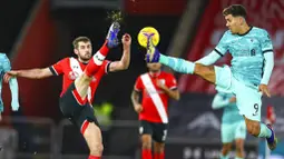 Pemain Southampton, Jack Stephens, berebut bola dengan penyerang Liverpool, Roberto Firmino, pada laga Liga Inggris di Stadion St Mary's, Selasa (05/01/2021). Liverpool takluk 1-0 dari Southampton. (AP Photo/Michael Steele,Pool)