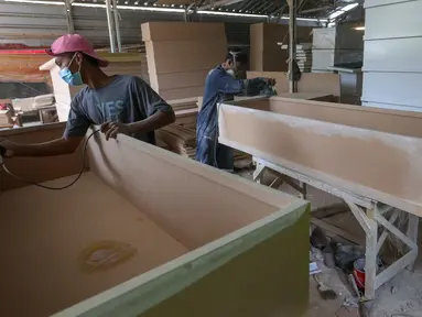 Pekerja menyelesaikan pembuatan peti mati Covid-19 di Rawa Mekar Jaya, Serpong, Tangerang Selatan, Kamis (21/01/2021). Produksi peti mati berbahan baku papan MDF meningkat cukup tinggi sejak bulan November 2020. (Liputan6.com/Fery Pradolo)