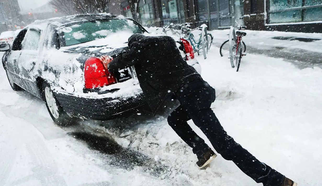 Seorang pria mendorong mobilnya saat badai salju melanda kawasan Brooklyn, New York City, AS (9/2). Ribuan sekolah negeri di New York dan Boston diliburkan untuk mengantisipasi datangnya badai salju. (Spencer Platt / Getty Images / AFP)