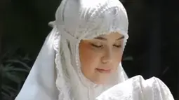 Gaya hijab yang dikenakan Annisa Pohan dalam foto ini adalah model mukena berwarna putih polos dengan desain sederhana namun elegan. Mukena ini memiliki potongan yang longgar dan nyaman, dengan aksen renda di bagian bawah yang menambah kesan anggun. (Liputan6.com/IG/@annisayudhoyono)