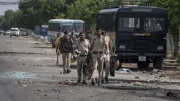 Pecahan kaca dan puing-puing berserakan di jalan saat polisi berpatroli setelah bentrokan komunal di Nuh di negara bagian Haryana, India, Selasa, 1 Agustus 2023. (AP Photo/Altaf Qadri)