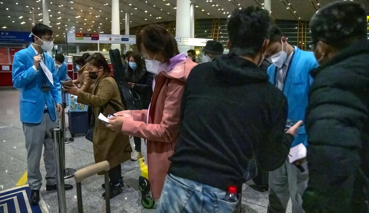 Pekerja membantu pelancong mengisi status kesehatan elektronik COVID-19 mereka di area kedatangan internasional di Bandara Internasional Beijing, China (9/1/2023). Pelancong internasional pertama tiba di China tanpa karantina wajib yang telah diberlakukan pada awal penerbangan. Pandemi tiga tahun lalu setelah pembatasan dicabut mulai hari Minggu. (AP/Mark Schiefelbein)