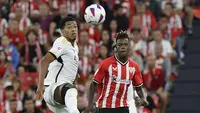Pemain Real Madrid, Jude Bellingham, berebut bola dengan pemain Athletic Bilbao, Nico Williams, pada laga pekan ke-1 La Liga 2023/2024 di Stadion San Mames, Minggu (13/8/2023). Los Blancos menang dengan skor 2-0. (AP Photo/Alvaro Barrientos)