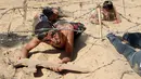 Seorang anak Palestina merangkak di bawah kawat berduri selama latihan militer di sebuah kamp musim panas yang diselenggarakan oleh Islamic Jihad Movement di Khan Younis di Jalur Gaza selatan (13/7). (REUTERS/Ibraheem Abu Mustafa)