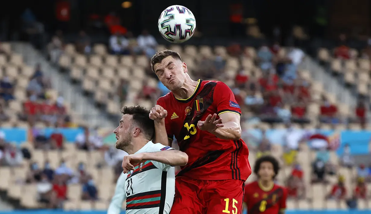 Pemain depan Portugal, Diogo Jota (kiri) melompat untuk menyundul bola saat berebut dengan bek Belgia Thomas Meunier pada babak 16 besar Euro 2020 di Estadio La Cartuja, Sevilla, Senin (28/6/2021) dini hari WIB. Belgia mendepak juara bertahan Portugal berkat kemenangan 1-0. (Julio Munoz/POOL/AFP)