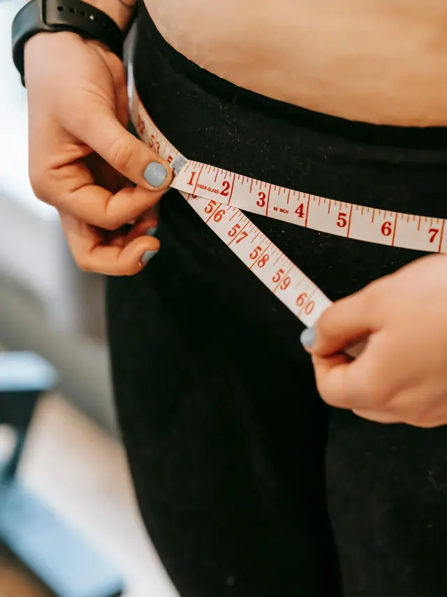 Wanita mengukur lingkar perutnya