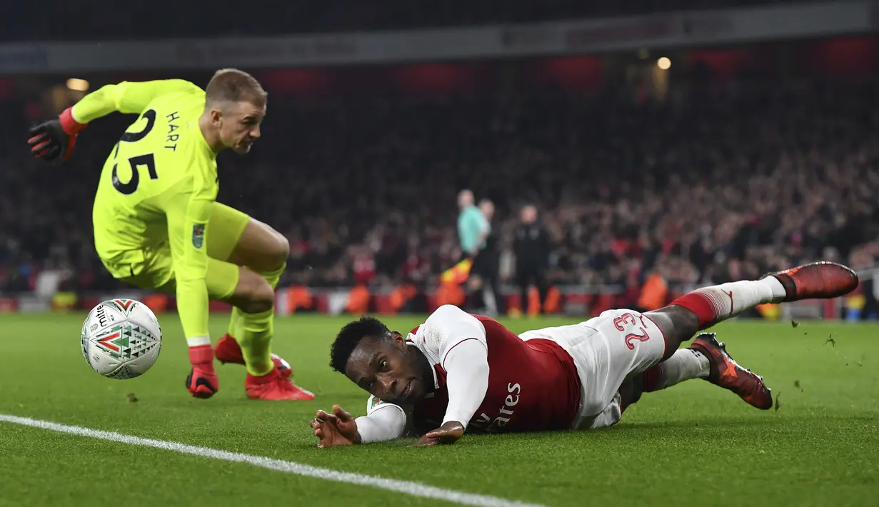 Pemain Arsenal, Danny Welbeck (kanan) jatuh saat berebut bola dengan kiper West Ham United, Joe Hart pada laga Piala Liga Inggris di Emirates Stadium, London, (19/12/2017). Arsenal menang 1-0. (AFP/Ben Sransall)