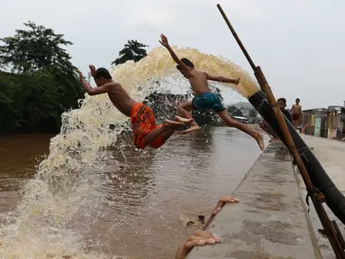Sejumlah anak bermain di bantaran kali Ciliwung, Kampung Pulo, Jakarta Timur, Sabtu (12/3). Warga memanfaatkan lahan di aliran sungai untuk tempat bermain karena minimnya lahan kosong di sekitar wilayah itu.(Liputan6.com/Gempur M Surya)