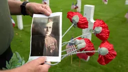 Mark Shively menunjukkan foto kakeknya dari Korps Marinir AS saat upacara Hari Peringatan Perang Dunia I di Pemakaman Amerika Aisne-Marne di Belleau, Prancis (27/5). (AP Photo / Virginia Mayo)