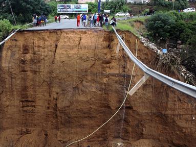 Orang-orang yang terlantar berdiri dekat jembatan yang hanyut di Ntuzuma, luar Durban, Afrika Selatan, 12 April 2022. Hujan berkepanjangan dan banjir di Provinsi KwaZulu-Natal Afrika Selatan telah merenggut puluhan nyawa, menurut pejabat setempat. (AP Photo)