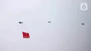 Helikopter TNI AU mengibarkan bendera Trimatra raksasa di kawasan Gedung DPR RI, Jakarta, Selasa (5/10/2021). TNI AU mengerahkan enam helikopter yang membawa bendera Merah Putih serta bendera Trimatra raksasa. (Liputan6.com/Faizal Fanani)