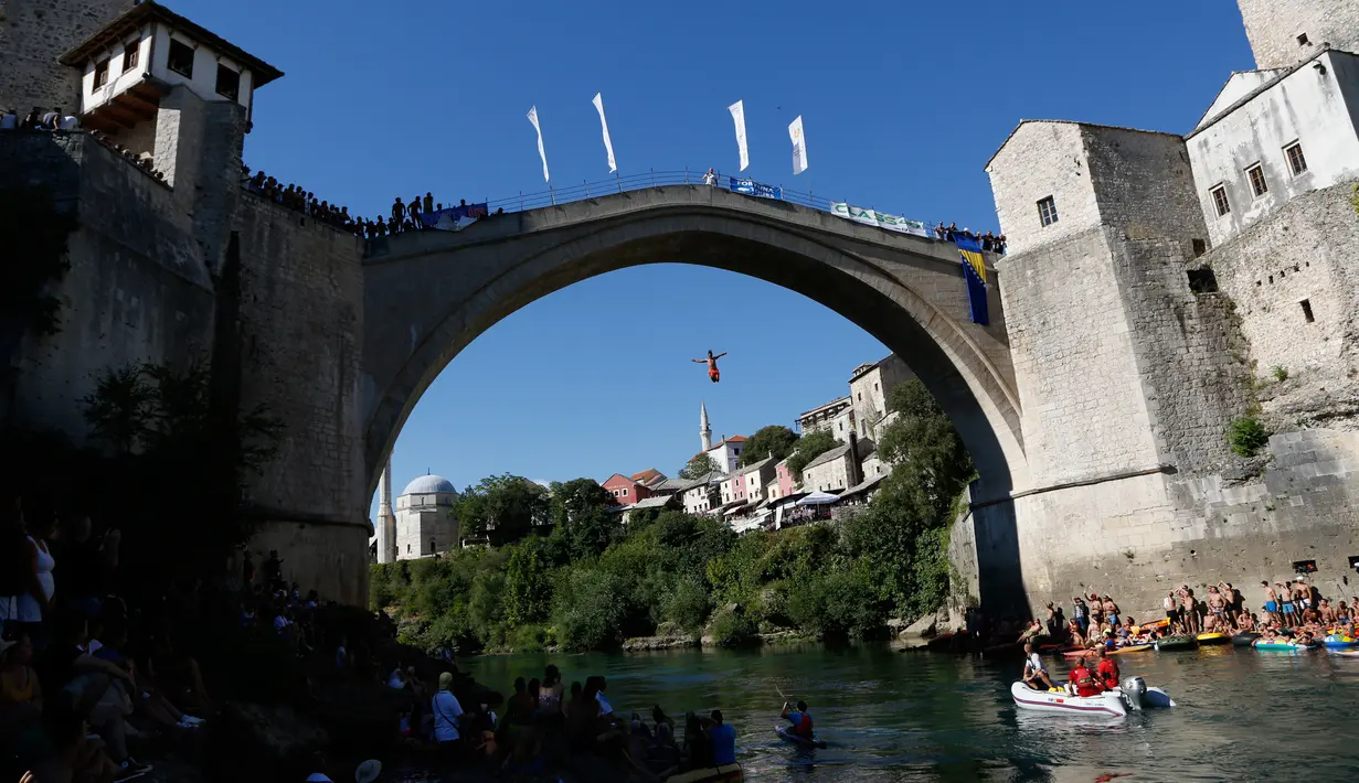 Penonton menyaksikan peserta melompat dari jembatan Mostar pada kompetisi menyelam tradisional ke 451 di Mostar, Bosnia, Minggu (30/7). Para peserta dari Bosnia dan negara tetangga itu melakukan lompatan dari ketinggian 25 meter. (AP Photo/Amel Emric)