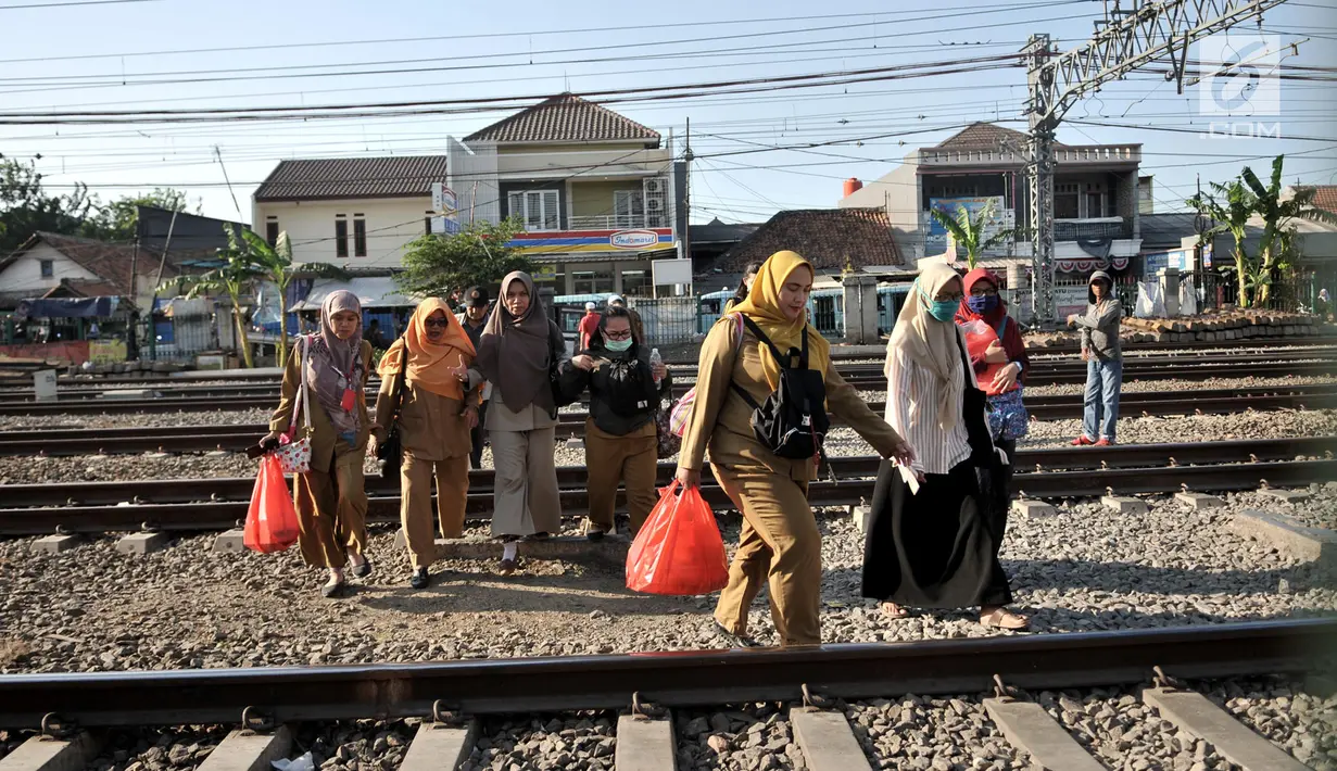 Ibu-ibu menyeberangi perlintasan rel kereta api di kawasan Pisangan Baru, Jakarta, Selasa (10/9/2019). Mereka nekat menantang maut menyeberangi rel di dekat stasiun Jatinegara tersebut lantaran tidak adanya akses jembatan penyeberangan orang (JPO). (merdeka.com/Iqbal Nugroho)