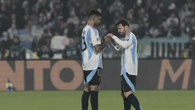 Cristian Romero dari Argentina menyerahkan ban kapten kepada Lionel Messi