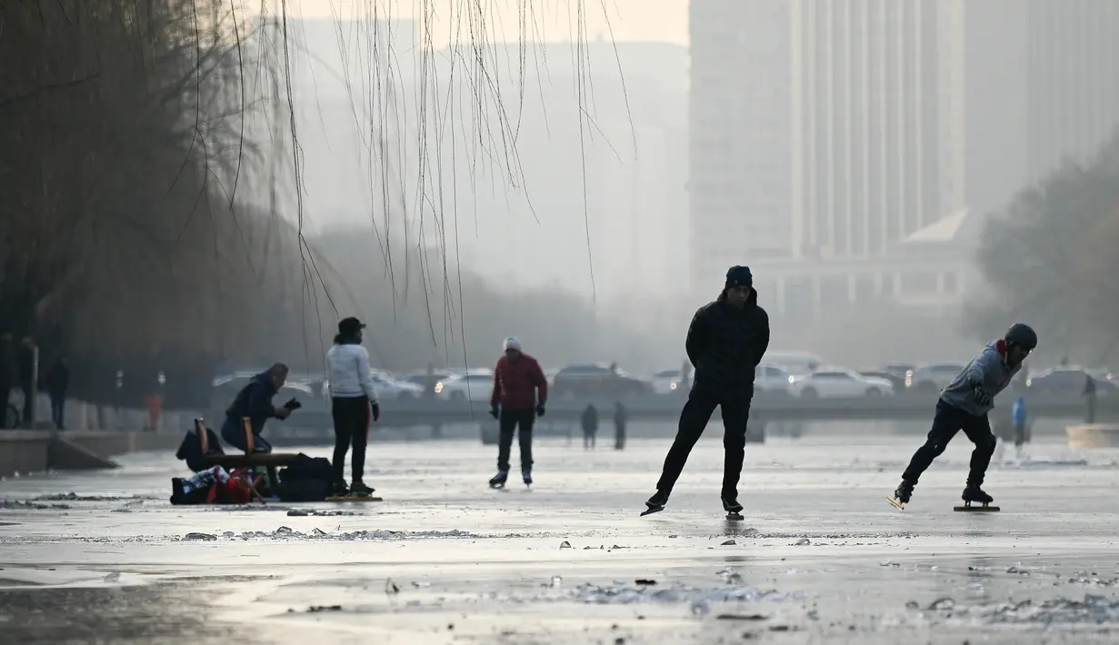 Sejumlah warga bermain ice skating di sungai yang membeku di Beijing, China (10/1). Akibat membeku, Sungai ini menjadi objek wisata dadakan. (AFP Photo/Wang Zhao)
