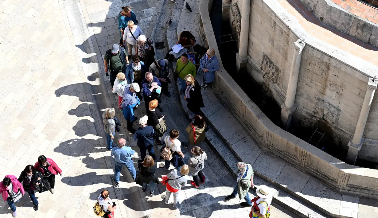 Para turis mendengarkan pemandu mereka di  Stradun, jalan utama kota tua Dubrovnik, di Kroasia. Dubrovnik kini semakin dikenal wisatawan setelah menjadi latar belakang film serial Game of Thrones sejak 2011 untuk jejaring televisi HBO. (Denis LOVROVIC / AFP)