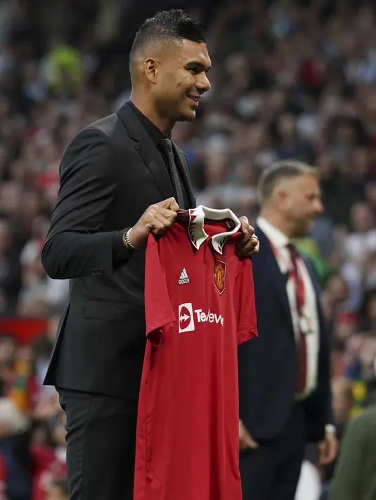 Pemain baru Manchester United Casemiro memegang jerseynya sebelum sesaat sebelum laga MU vs Liverpool dimulai di stadion Old Trafford, di Manchester, Inggris, Senin (22/8/2022). Casemiro yang berpakaian serba hitam, mulai dari jas sampai kemeja yang dikenakannya, berjalan menuju tengah lapangan. (AP Photo/Dave Thompson)