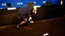 Seorang karyawan mengumpulkan uang kertas yang dilemparkan oleh Lee Nelson di markas FIFA di Zurich, Swiss, (20/7/2015). Blatter untuk pertama kalinya mengadakan jumpa pers sejak menyatakan akan mundur sebagai presiden FIFA.(REUTERS/Arnd Wiegmann)