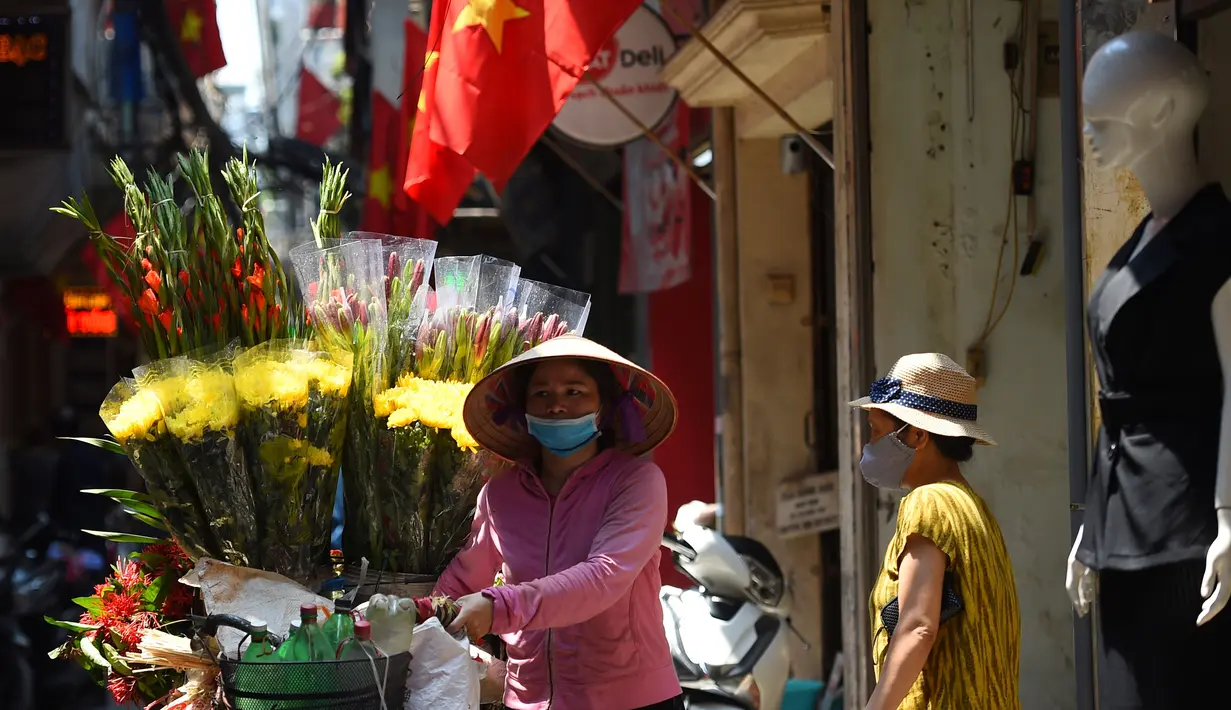 Seorang pedagang kaki lima melewati gang yang didekorasi dengan bendera nasional Vietnam menjelang perayaan Hari Nasional Vietnam di Hanoi (1/9/2020). Peringatan 75 tahun Hari Nasional Vietnam jatuh pada tanggal 2 September 2020. (AFP Photo/Nhac Nguyen)
