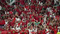 Suporter Maroko memberikan dukungan kepada timnya saat laga babak 16 besar Piala Dunia 2022 melawan Spanyol yang berlangsung di Education City Stadium, Selasa (06/12/2022). (AP/Ebrahim Noroozi)