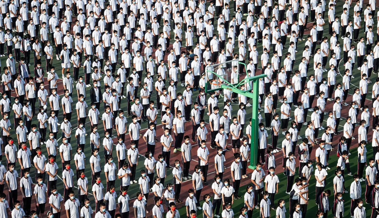 Foto dari udara menunjukkan para siswa menghadiri upacara pembukaan pada hari pertama semester baru di Wuhan, Provinsi Hubei, China, 1 September 2021. Pemerintah China memutuskan pemberlakuan belajar tatap muka setelah percaya diri menangani pandemi COVID-19. (STR/AFP)