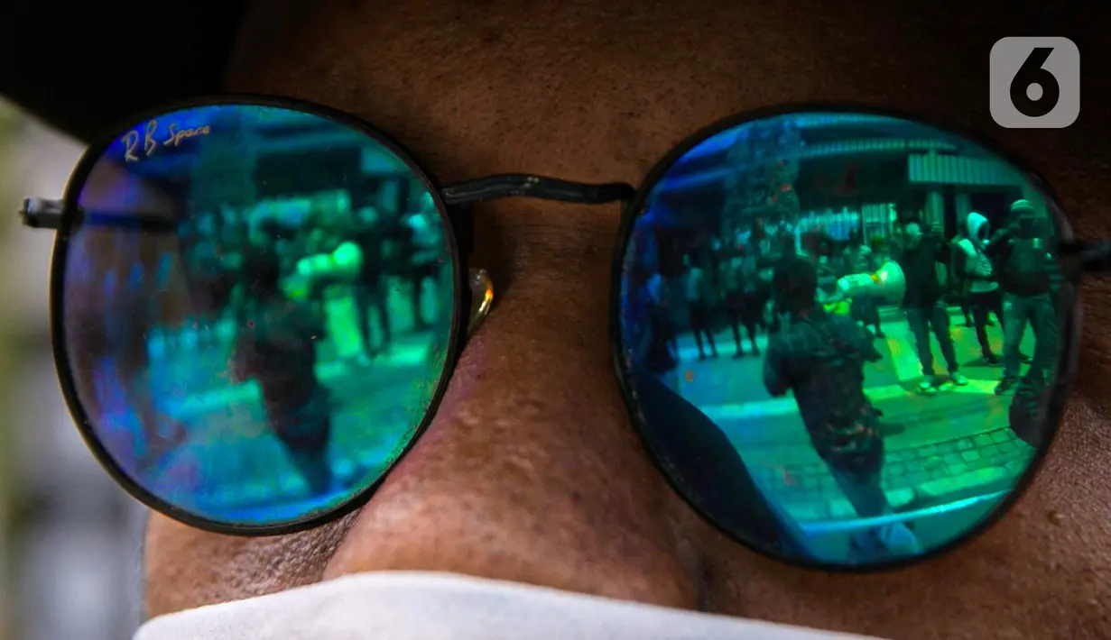 Refleksi gambar pada kaca mata memperlihatkan aksi Ikatan Mahasiswa Papua yang menggelar unjuk rasa di depan Kementerian Dalam Negeri, Jakarta, Rabu (24/2/2021). Massa mengutuk tindakan elite politik Papua yang mengatasnamakan rakyat Papua untuk mendukung Otonomi Khusus. (Liputan6.com/Faizal Fanani)