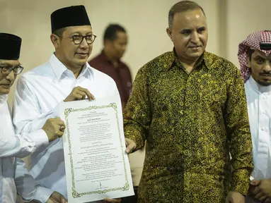 Menag Lukman Hakim Saifuddin menunjukan surat yang usai ditanda tangani saat meresmikan pemajangan potongan Kiswah (kain penutup Kakbah) hadiah dari Raja Salman bin Abdulaziz Al Saud di Masjid Istiqlal, Jakarta, Jumat (10/3). (Liputan6.com/Faizal Fanani)