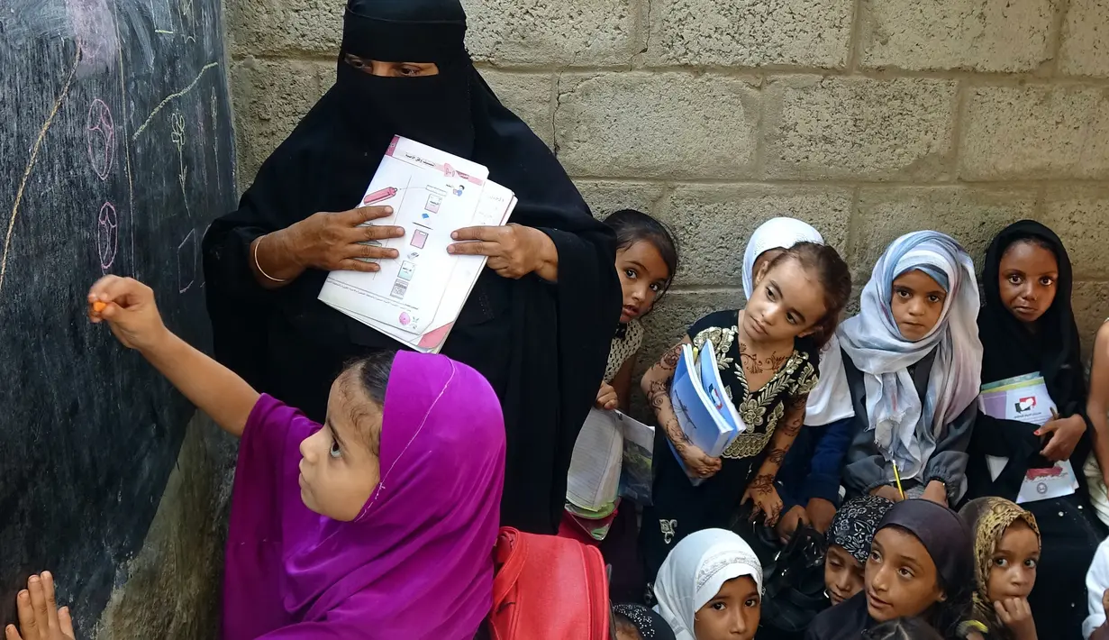 Seorang anak saat menulis di papan tulis di gedung sekolah yang terlihat rusak di provinsi barat Hodeidah, Yaman, Minggu (5/9/2021). Konflik antara pemerintah dan pemberontak Houthi menjadi penyebabnya. (AFP/Khaled Ziad)