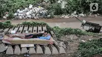 Seorang tunawisma tidur di lapaknya di kolong rel dwi ganda atau double-double track (DDT), kawasan Manggarai, Jakarta, Kamis (7/1/2021). Mereka yang terpaksa berprofesi sebagai pemulung memilih tinggal di sana akibat ketimpangan sosial yang semakin tinggi di Ibu Kota. (merdeka.com/Iqbal S. Nugroho)