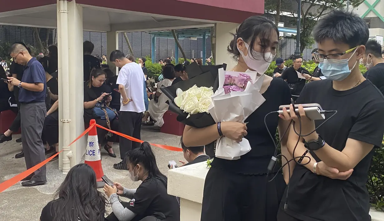 Di luar rumah duka di bagian timur pulau Hong Kong, hampir seribu penggemar, banyak yang berpakaian hitam, mengantri di tengah teriknya cuaca untuk memasuki aula pemakaman yang dibuka untuk umum setelah kebaktian pribadi. (AP Photo/Annie Cheung)