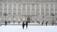 Dua gadis berlari melewati salju di luar Istana Kerajaan, Madrid, Spanyol, Jumat (8/1/2021). Salju tebal menutupi hingga setengah dari Spanyol dan menyebabkan penurunan suhu yang besar. (GABRIEL BOUYS/AFP)