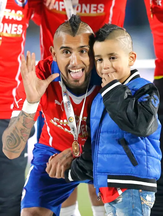 Arturo Vidal bersama anaknya merayakan kemenangan negaranya usai mengalahkan Argentina di Final Copa America 2015 di Stadion Nasional, Chili, (4/7/2015). Chili menang lewat adu penalti atas Argentina dengan skor 4-1. (REUTERS/Henry Romero)