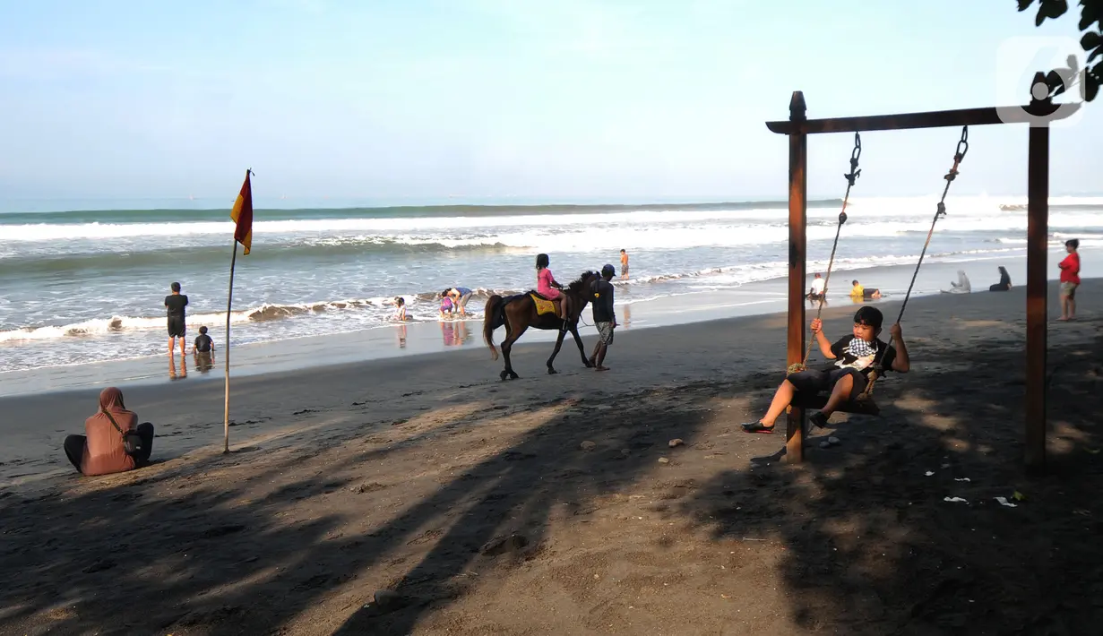 Seorang anak bermain ayunan di pinggir pantai di kawasan Pantai Karang Naya, Pelabuhan Ratu, Sukabumi, Selasa (1/6/2021). Walaupun liburan lebaran telah usai sejumlah pantai di kawasan Pelabuhan Ratu masih dipadati pengunjung yang berasal dari Kota Jakarta dan Jawa Barat.(merdeka.com/Arie Basuki)