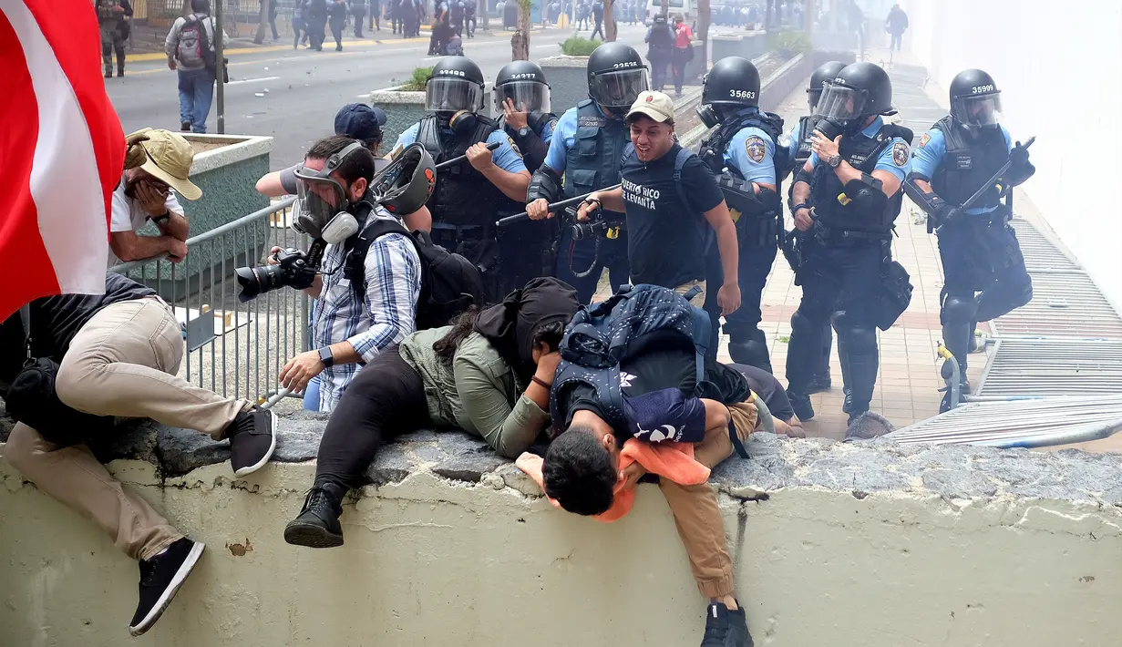 Polisi anti huru hara menyemprotkan gas air mata kearah pengunjuk rasa saat terjadi aksi demonstrasi pada peringatan Hari Buruh di San Juan, Puerto Rico (1/5). (AFP/Ricardo Arduengo)