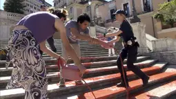Para aktivis hak-hak perempuan memprotes feminisme dengan mengecat Spanish Steps yang terkenal di Roma dengan warna merah, yang secara simbolis melambangkan darah para perempuan korban kekerasan. (Lapresse via AP)