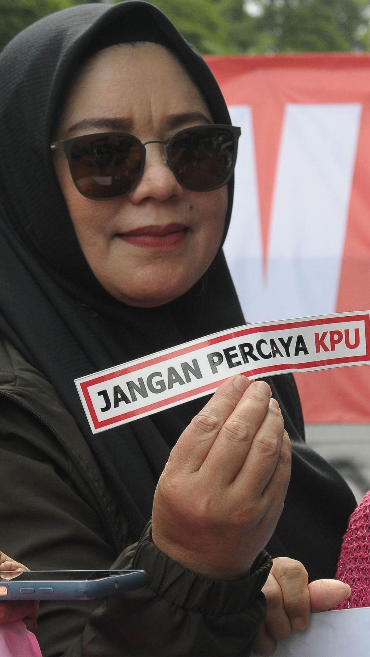 Pendemo menunjukkan sebuah label bertuliskan "Jangan Percaya KPU" saat melakukan aksi di depan Kantor Komisi Pemilihan Umum (KPU), Jakarta, Senin (18/3/2024). Foto: merdeka.com / Imam Buhori