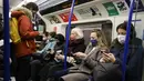 Penumpang melakukan perjalanan dengan kereta bawah tanah Transport for London (TfL) Victoria Line menuju pusat kota London (5/1/2022). Rumah sakit Inggris telah kekurangan staf yang disebabkan oleh gelombang infeksi Omicron, kata pemerintah pada hari Selasa (4/1). (AFP/Tolga Akmen)