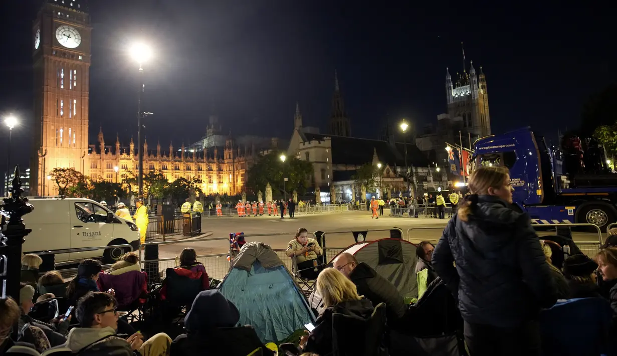 Orang-orang berkemah di depan Istana Westminster pada malam pemakaman Ratu Elizabeth II di London, Minggu, 18 September 2022. Pemakaman Ratu Elizabeth II, raja terlama di Inggris, berlangsung pada Senin (19/9). (AP Photo/Christophe Ena)