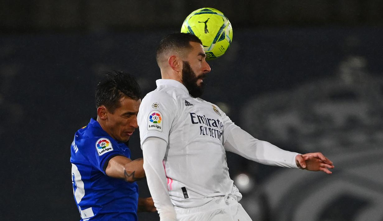 Striker Real Madrid, Karim Benzema (kanan) berduel udara dengan bek Getafe, Damian Suarez dalam laga lanjutan Liga Spanyol 2020/21 pekan ke-22 di Alfredo di Stefano Stadium, Selasa (9/2/2021). Real Madrid menang 2-0 atas Getafe. (AFP/Gabriel Bouys)