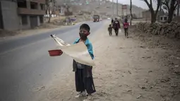 Keyler Martinez, memohon sambil memegang bendera putih yang menandakan kebutuhan mendesak akan makanan selama pandemi virus corona di pinggir jalan di pinggiran kota Lima, Peru (22/8/2020).  (AP Photo/Rodrigo Abd)