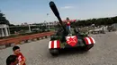 Suporter Red Star Belgrade berpose di tank T-55 yang terparkir di tribun utara Stadion Rajko Mitic, Belgrade, Serbia, Selasa (27/8/2019). Tank buatan Uni Soviet tersebut milik tentara Yugoslavia yang digunakan dalam perang saudara pada tahun 1990. (AP Photo/Darko Vojinovic)