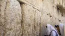 Pria berdoa di depan catatan doa yang ditinggalkan oleh jemaah lainnya di celah-celah Tembok Barat, tempat doa paling suci Yudaisme, di Kota Tua Yerusalem, Rabu (25/8/2021). (AP Photo/Ariel Schalit)