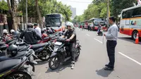 Para calon calon penumpang memarkir motornya di titik lokasi Balai Kota Surabaya untuk menaiki shuttle bus penonton menuju Stadion Gelora Bung Tomo untuk menyaksikan pembukaan Piala Dunia U-17 2023 sekaligus laga Timnas Indonesia U-17 menghadapi Ekuador, Jumat (10/11/2023). (Bola.com/Bagaskara Lazuardi)