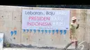 Berbagai macam tulisan bertema lebaran hiasi tembok dinding tanggul Sungai Ciliwung (Liputan6.com/Faizal Fanani)