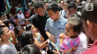 Calon wakil presiden nomor urut 2 Gibran Rakabuming Raka membagikan buku kepada anak-anak saat blusukan di kawasan Warakas, Jakarta, Selasa (16/1/2024). Gibran melakukan kegiatan tersebut dengan membagi buku dan berbincang dengan warga. (Liputan6.com/Herman Zakharia)