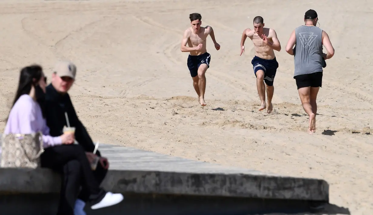 Warga bersantai dan berolahraga di sebuah pantai di Melbourne, Australia, Kamis (19/8/2021). Melbourne melewati 200 hari dalam lockdown keras sejak dimulainya pandemi COVID-19. (William WEST/AFP)