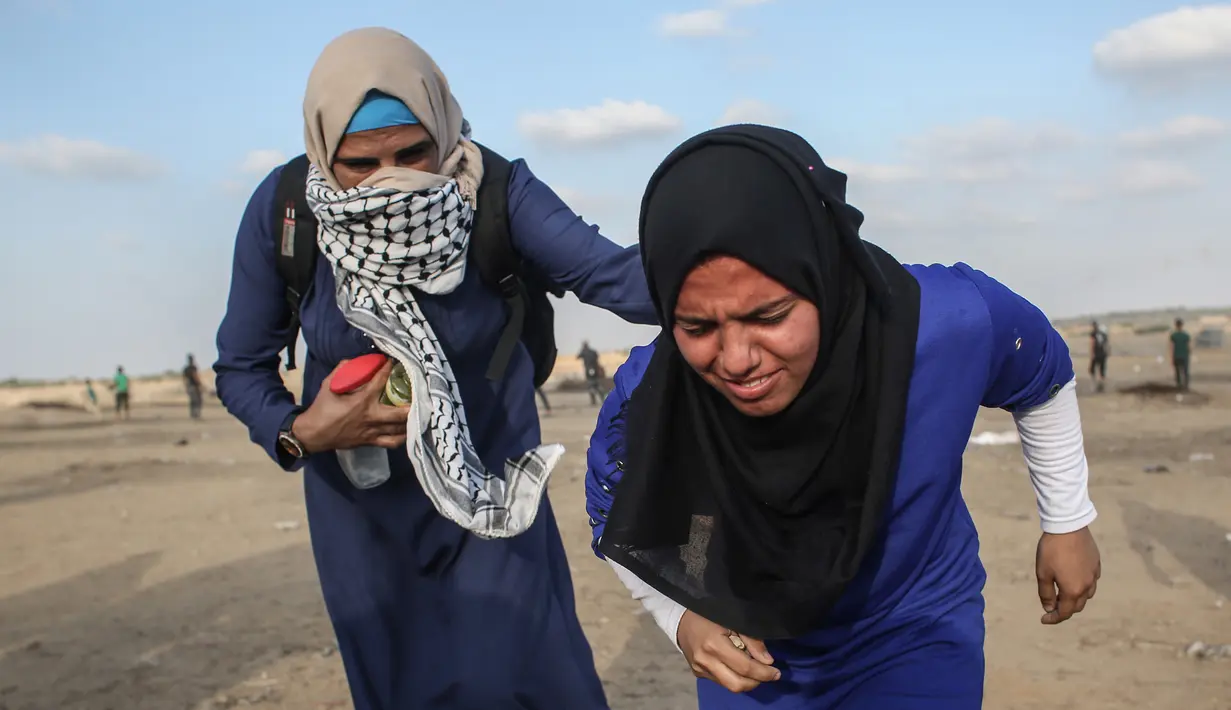 Wanita Palestina berlari saat pasukan Israel menembakkan gas air mata dalam bentrok di Khan Yunis, Jalur Gaza, Jumat (13/9/2019). Aksi yang dikenal dengan Great March of Return ini diluncurkan sejak Maret 2018. (SAID KHATIB/AFP)