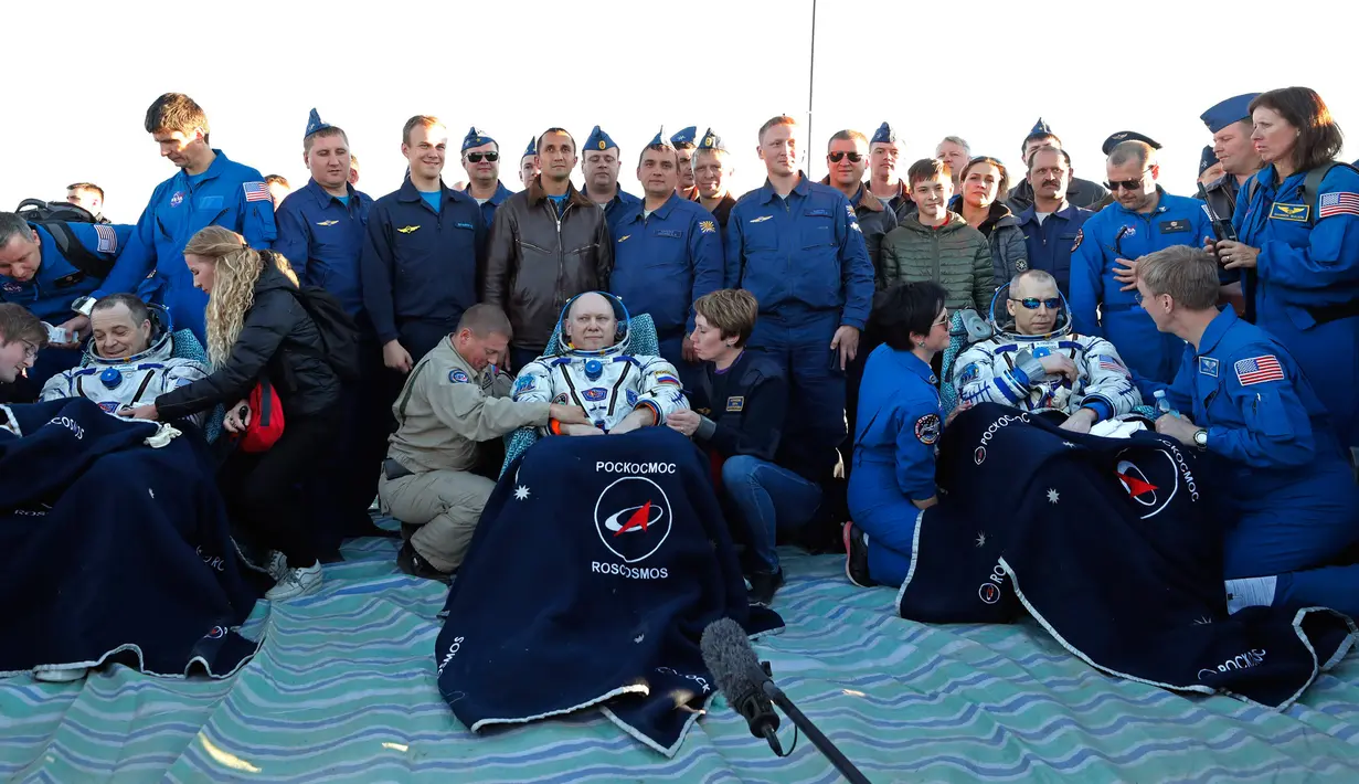 Astronot AS Richard Arnold (kiri) dan Andrew Feustel (kanan) serta kosmonot Rusia Oleg Artemyev (tengah) beristirahat sesaat setelah kapsul ruang angkasa Soyuz MS-08 mendarat di luar Kota Dzhezkazgan, Kazakhstan, Kamis (4/10). (Maxim Shipenkov/Pool/AFP)